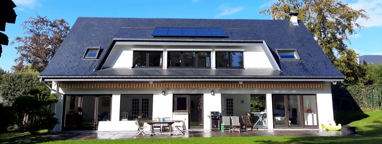 Villa blanche avec des panneaux solaires sur une toiture en ardoises